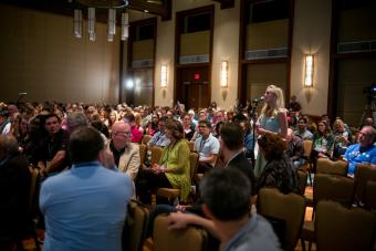 A woman asks a question into a microphone at a conference